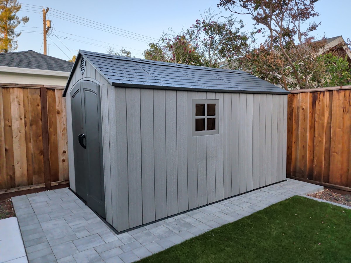 Gray backyard storage shed assembled on a paved base